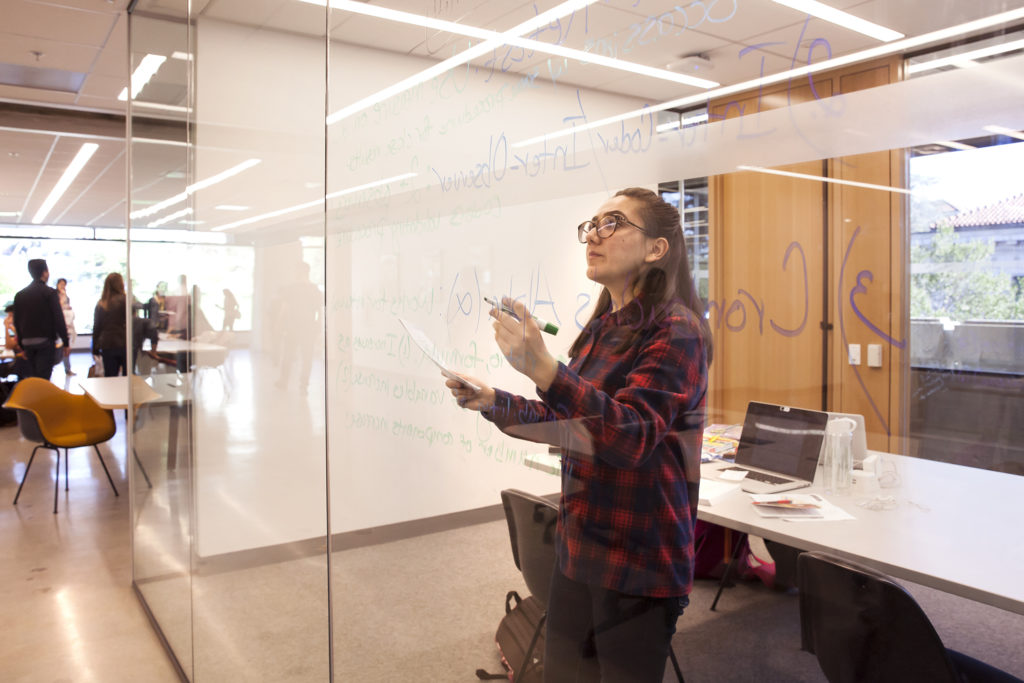 Saamia Haqiq, a UC Berkeley senior majoring in political science, makes use of the writeable glass walls during her study time. “This is definitely my new favorite space,” says Haqiq. (Photo by Brittany Hosea-Small for the University Library)