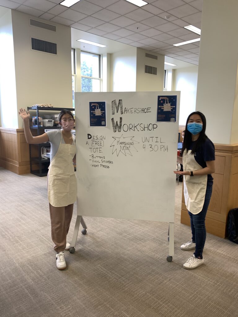 Chloe and Alysa standing by a whiteboard advertising their Making event.