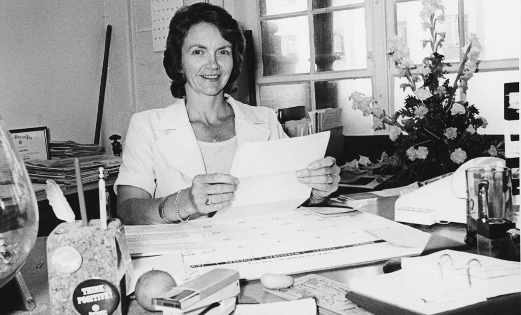 Luella Lilly at her desk, holding up a piece of paper