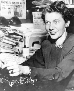 Mary Ellen Leary at desk with typewriter and numerous papers