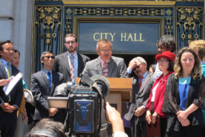 Norman Yee speaking to crowd in front of City Hall in San Francisco