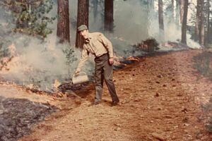 Color photograph of a person lighting a controlled burn