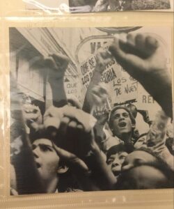 Protest photograph from the Acción Latina archive: young men with fists raised in air