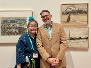 Two people standing in front of framed artwork