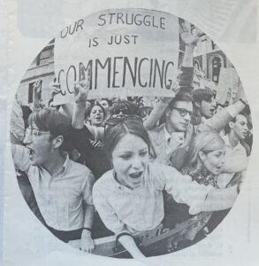 Black and white photograph of students with a sign saying, "our struggle is just commencing"